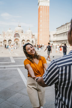 Loving couple on vacation in Piazza San Marco, Venice, Italy - The woman pulls the man towards her