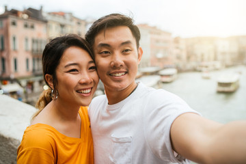 Loving couple on vacation in Venice, Italy - Millennials take a selfie on the famous Rialto Bridge