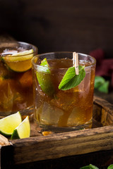 Whiskey Cola cocktail with lime, mint and ice i glass. Rum, alcohol, Cuba Libre, brandy. Bar on dark background