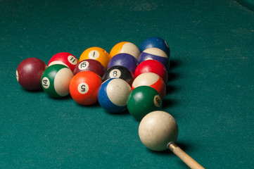 Billiard balls and a stick on a green table. Billiard balls isolated on a green background