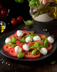 Caprese salad with mini mozzarella, juicy tomato and fresh Basil. Delicious Italian snack,...