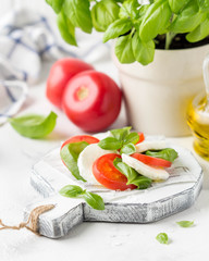Caprese salad with mozzarella, juicy tomato and fresh Basil. Delicious Italian snack, traditional food. On light background