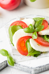 Caprese salad with mozzarella, juicy tomato and fresh Basil. Delicious Italian snack, traditional food. On light background