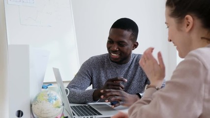 Two positive mixed race students of the faculty of foreign languages are working on a joint presentation on the laptop. Concept of joint study and new knowledge