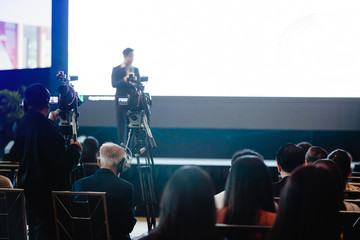 blurry image of business people and cameraman with video camera set are recording to speaker and...