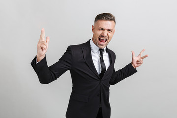 Image of successful excited businessman in formal suit screaming and gesturing peace sing