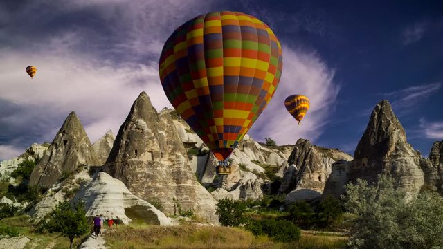 Cinemagraph of hikers in Cappadocia, Turkey, with balloons set against swirling cloud motion.
