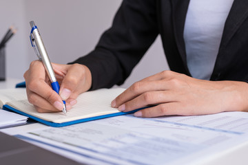 The woman is writing a message in the book on table. He is now sitting business plan that has new idea in the morning. Concept idea planing and analyzes.