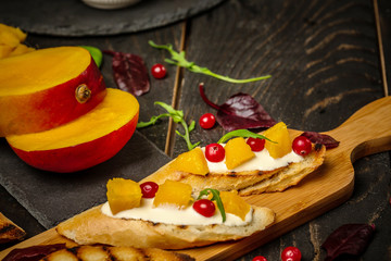 Bruschetta with sweet mango, pomegranate, cheese. on wooden background. Healthy food, Flat top view