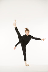 A girl in black clothes and Pointe shoes on a white isolated background performs dance and ballet poses and movements.