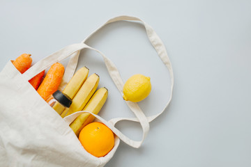 Fresh organic fruit and vegetables in a linen bag on a light grey background. Eco lifestyle, zero waste concept. No plastic living.
