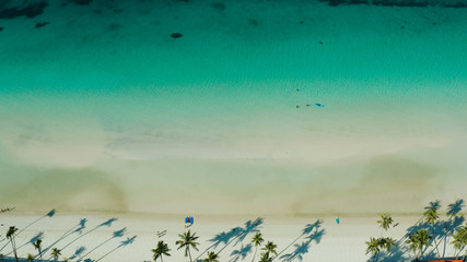 White sandy beach with tourists and azure water of the lagoon,copy space for text, top view. Ocean with waves and tropical beach. Summer and travel vacation concept