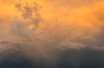 Dramatic clouds of thunderstorm in orange sunlight. Sunset on summer evening.