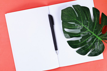notebook coral background, tropical leaf. Top view, flat lay. copy space. Summer background, travel.