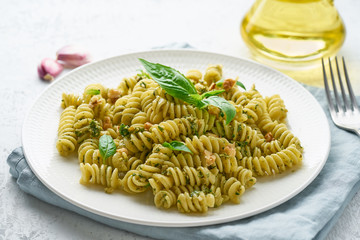 fusili pasta with basil pesto and herbs, italian cuisine, gray stone background, closeup