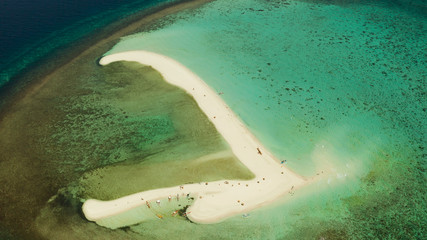 Beautiful beach on tropical island surrounded by coral reef, sandy bar with tourists, top view. Sandbar Atoll. Summer and travel vacation concept, Camiguin, Philippines.
