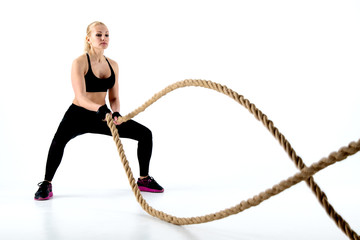 Beautiful athlete performs an exercise with a rope.
