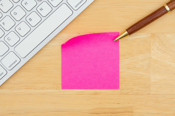 Sticky note with a keyboard with a pen on a desk