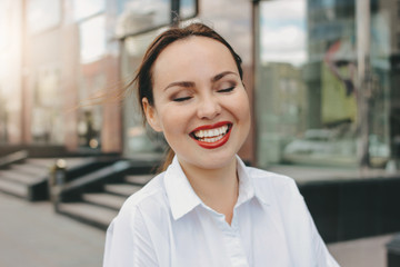 Close up portrait of happy brunette elegant woman business lady in white shirt at city street