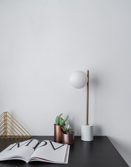 Composition of gold bookshelf and copper vase and gold stylish table lamp in mid century modern design standing on black wooden top with white background / interior design / composition background 