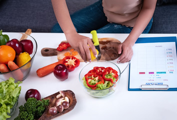 Fresh vegetable was preparing for salad meal by woman,healthy food,good for life,salad  bowl put beside blurred diet plan schedule,blurry light design background