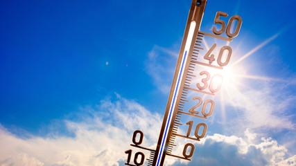Hot summer or heat wave background, bright sun on blue sky with thermometer