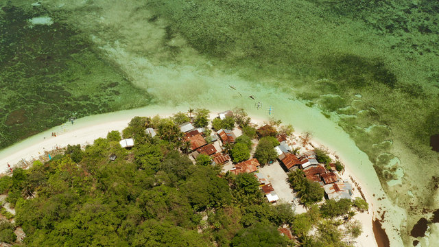 Tropical island and sandy beach surrounded by atoll coral reef and blue sea, aerial view. Small island with sandy beach. Summer and travel vacation concept, Mantigue Philippines Mindanao