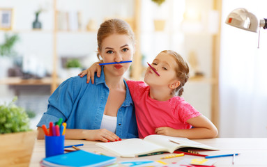 funny mother and child daughter doing homework writing and reading .