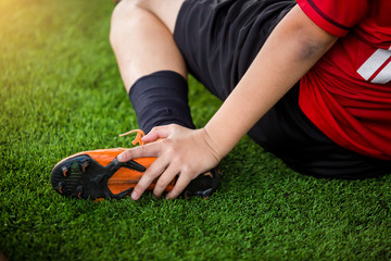footballer is sitting and catch the ankle of the feet because of pain, soccer player was injured in...