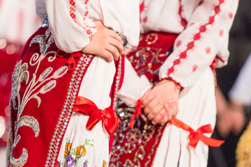 Fototapeta na wymiar Close up on hands of young Romanian dancers perform a folk dance in traditional folkloric costume. Folklore of Romania