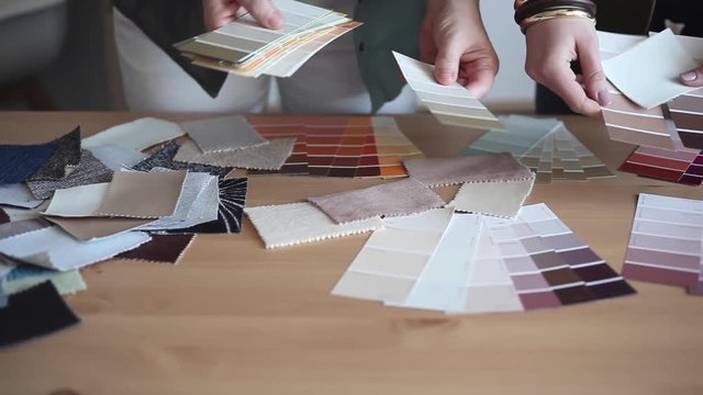 Two women designers choose from color palette and fabric samples the best for their client