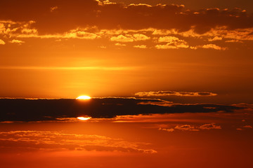 Fototapeta na wymiar Sunset on orange sky, sun shining through the dark clouds. Beautiful skyline for background