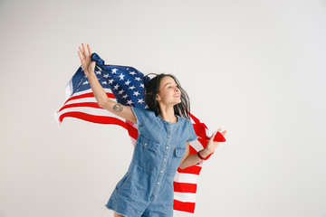 Celebrating an Independence day. Stars and Stripes. Young woman with the flag of the United States of America isolated on white studio background. Looks crazy happy and proud as a patriot of her