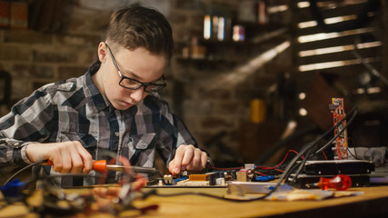 Portrait Shot of a Young boy is soldering a circuit board in a garage at home.