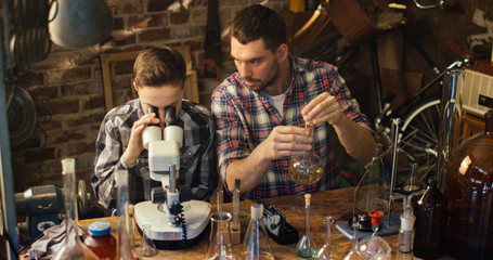 Father and son are making chemistry experiments while checking microscope in a garage at home.