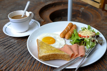English breakfast - fried egg, bacon, sausage, toast and coffee.