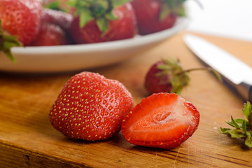 Ripe berries of garden wild strawberry close up. Whole and cut berries on a plate and on a Board