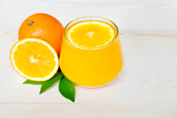Navel orange juice and slices of orange with leaves on wooden background