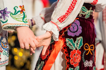 Close up of hands of young Romanian dancers perform a folk dance in traditional folkloric costume....