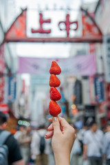 Close up hand hold skewer fresh sweet strawberry famous fruit Sold at Ameyoko market Ueno Tokyo.