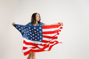 Celebrating an Independence day. Stars and Stripes. Young woman with the flag of the United States of America isolated on white studio background. Looks crazy happy and proud as a patriot of her