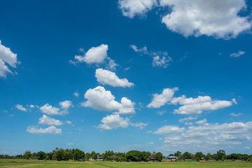 Blue sky background with green fields and white clouds.