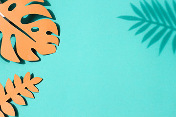 Paper tropical palm leaves on the pastel green background. Summer concept Top view