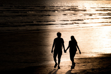 Silhouette Man and Girl hand in hand walk together at Seaside in Krabi Province , Thailand On June 19,2019