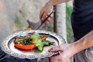 A man grills corn, pepper and asparagus. Concept - healthy food in the family, male hobby, a man prepares food.