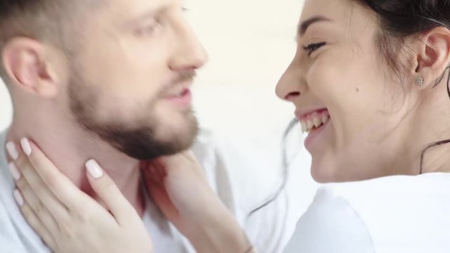 cheerful woman touching face and nose of happy bearded man isolated on white  