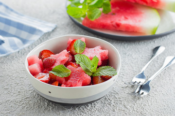 Summer salad with watermelon and strawberry on concrete background table, close-up