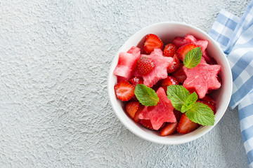 Summer salad with watermelon and strawberry on concrete background table, top view with copy space