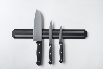 Magnetic holder with set of knives on grey stone background