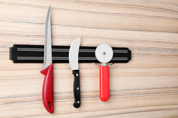 Magnetic holder with set of knives on wooden background